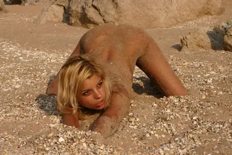 Blondýnka pózuje nahá na pláži, než vstoupí do oceánu