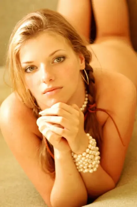 Showing her small breasts, slender Sabine A poses nude on a couch