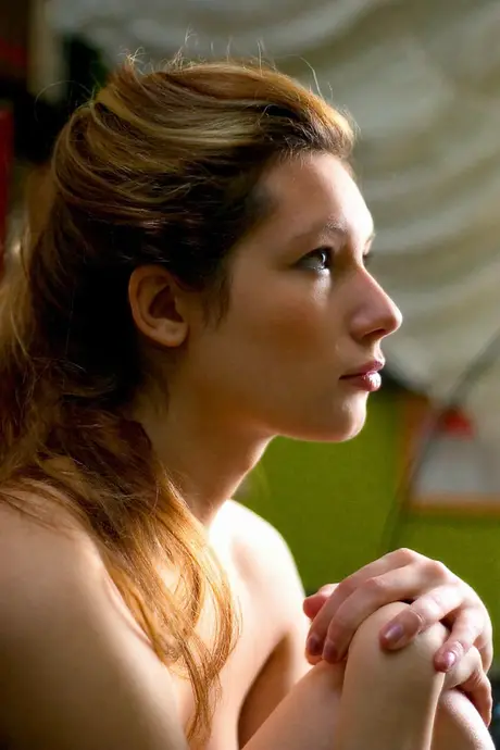A beautiful woman with long legs and a toned rear poses with no clothes on in a library