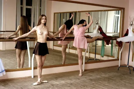 Ballerinas bare their small breasts during a barre stretch