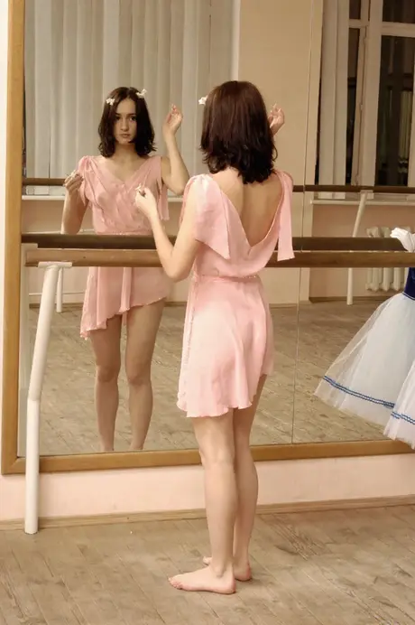 Ballerinas bare their small breasts while stretching at the barre