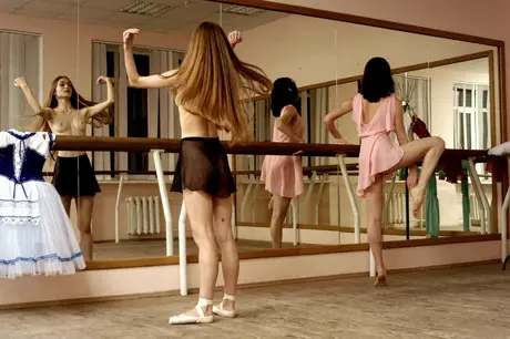 At the barre, ballerinas stretch and bare their small breasts