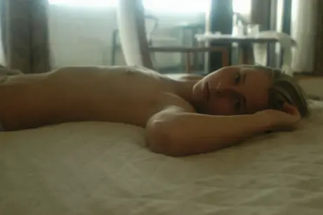 A young woman enjoys a soft drink and then strips completely on her bed