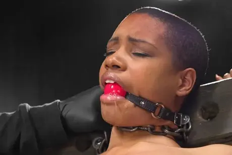 Soumise noire bâillonnée en bondage métallique baisée par machine