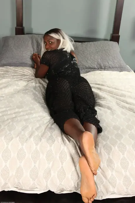 Une femme noire aux cheveux colorés se fait plaisir sur son lit après s'être déshabillée