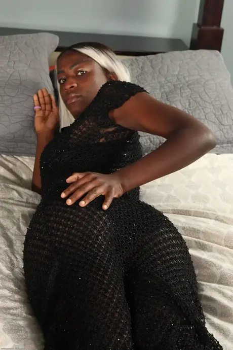 Une femme noire aux cheveux colorés se fait plaisir sur son lit après s'être déshabillée