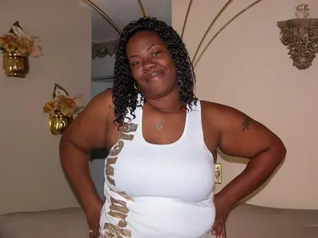 Een ebony BBW vingert haar geschoren kutje nadat ze zich heeft uitgekleed