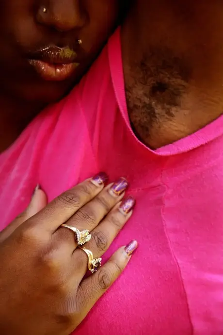 Een ebbenhouten vrouw onthult haar natuurlijke kutje terwijl ze op een tuinstoel zit