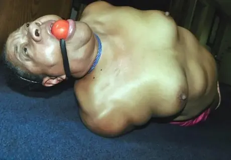 Trixie, en overvægtig sort kvinde, kæmper i en hogtie, mens hun bærer en boldgag