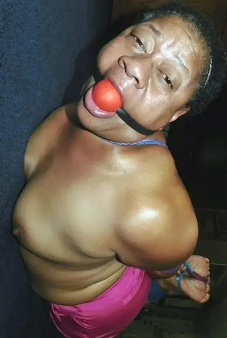 Trixie, en overvægtig sort kvinde, kæmper i en hogtie, mens hun bærer en boldgag
