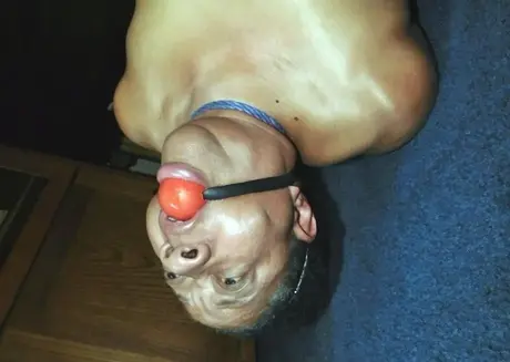 Trixie, en overvægtig sort kvinde, kæmper i en hogtie, mens hun bærer en boldgag
