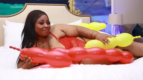 Simone Thyke in Dessous kuschelt mit Luftballons auf einem Bett