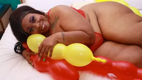 Simone Thyke in Dessous kuschelt mit Luftballons auf einem Bett