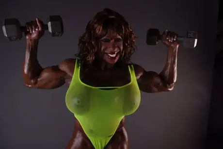 Yvette Bova, den mørkhudede bodybuilder, afslører sine enorme bryster under en vægtløftningssession