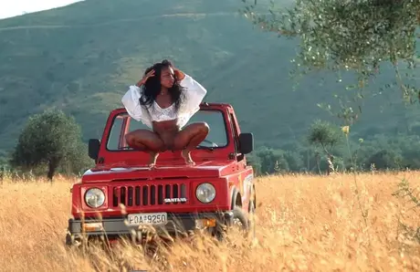 Diana-h, Afroameričanka v teenagerském věku, se svléká a pózuje na Jeepu během safari