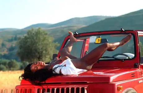 Diana-h, Afroameričanka v teenagerském věku, se svléká a pózuje na Jeepu během safari