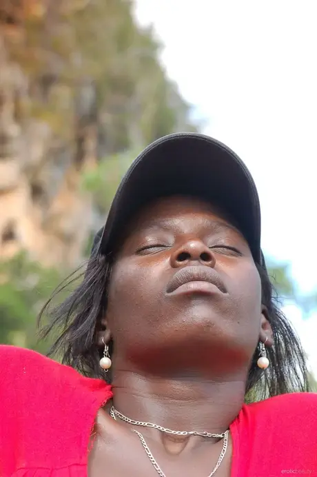 Ebony Maria L si sundá šortky a červené tričko a venku koketně ukazuje zadek