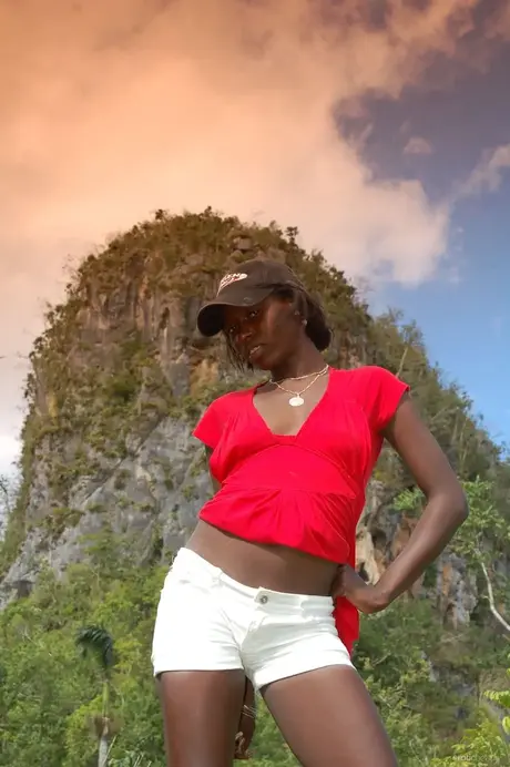 Ebony Maria L si sundá šortky a červené tričko a venku koketně ukazuje zadek
