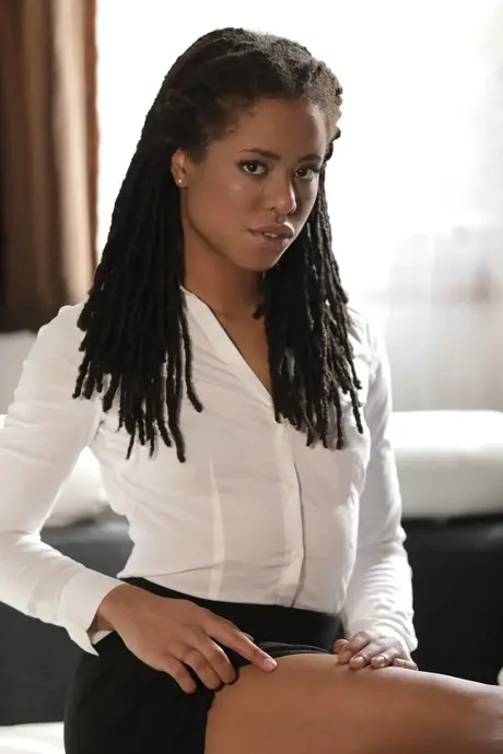 Kira Noir, ebony sólová modelka, odhaluje nohy a poté se svléká z kancelářského outfitu