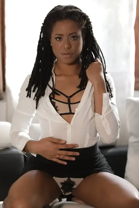 Kira Noir, ebony sólová modelka, odhaluje nohy a poté se svléká z kancelářského outfitu