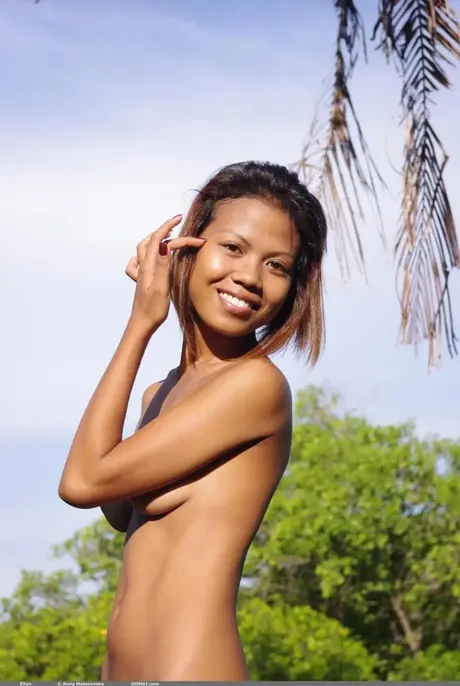 Asiatisches Model posiert völlig nackt im Schatten eines Baumkronendachs