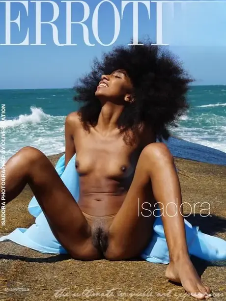 Isadora, ibenholtglamourmodellen, poserer nøgen ved havet med voluminøst stort hår