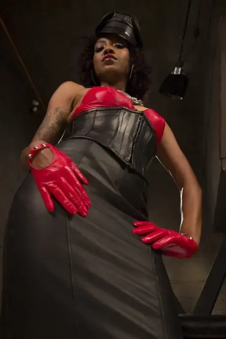 Lotus Lain, ebony femdom v kůži, ukazuje svá malá prsa a bradavky