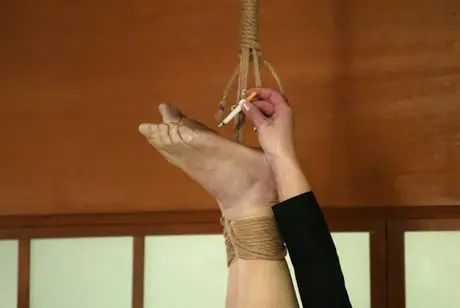 Janay stuzzica un uomo nudo legato mentre accende una sigaretta