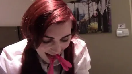 Zrzavá studentka s růžovými kolíčky na prádlo na jazyku a obojkem