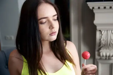 Brunette Phonexia kleedt zich volledig uit terwijl ze een lolly vasthoudt