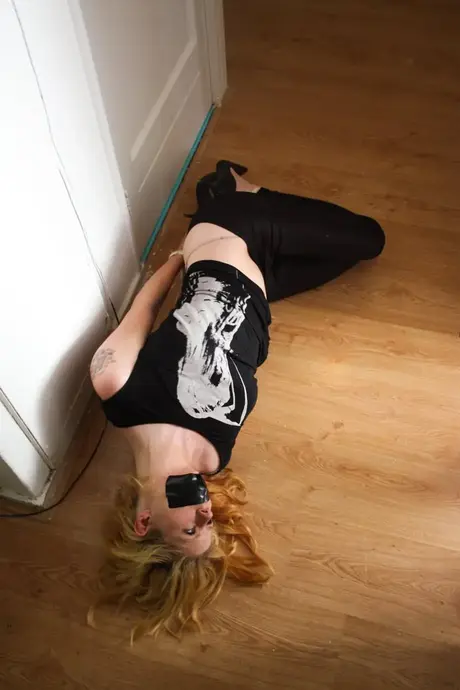 Cindy, blondýnka, je svázaná v hogtie s ucpanými a přelepenými ústy
