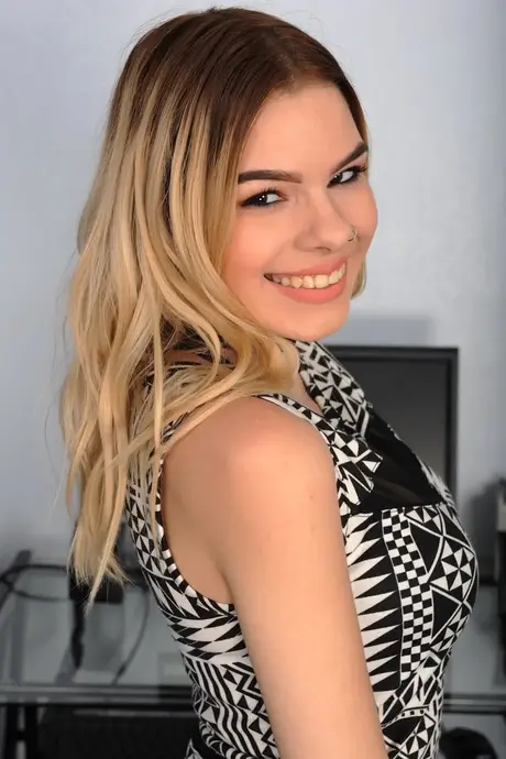 Pretty blonde Cora Ora strips naked and spreads her shaved pussy