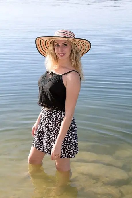 Amatorska kobieta Camille rozbiera się na piaszczystym brzegu plaży nudystów