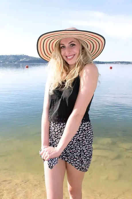 Amatorska kobieta Camille rozbiera się na piaszczystym brzegu plaży nudystów