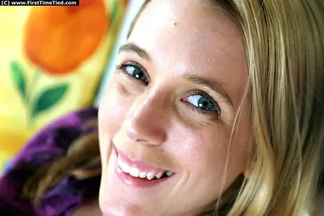 Mujer rubia con las manos atadas a la espalda y una mordaza de bola colocada