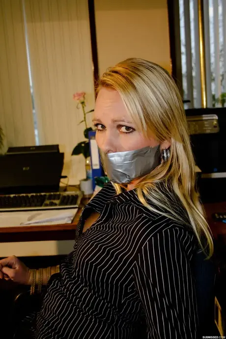 Vollbusige blonde Sekretärin Natalie an einen Stuhl gefesselt, während sie im Büro posiert