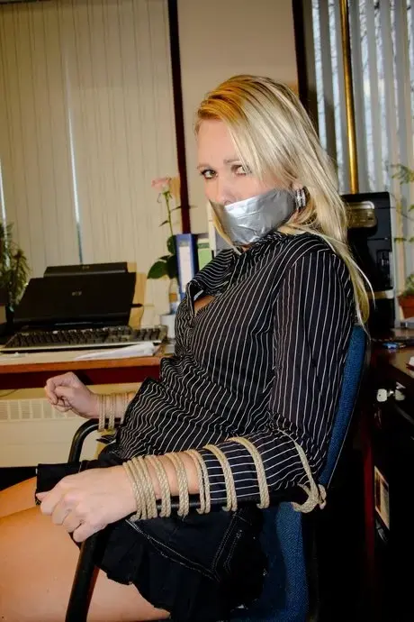 Vollbusige blonde Sekretärin Natalie an einen Stuhl gefesselt, während sie im Büro posiert