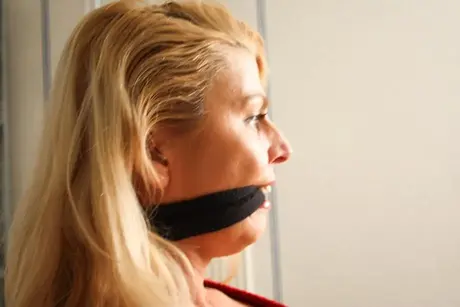 La magnifique blonde Adrienne attachée à une chaise en crop top et jean serré