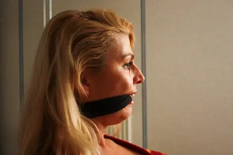 La magnifique blonde Adrienne attachée à une chaise en crop top et jean serré