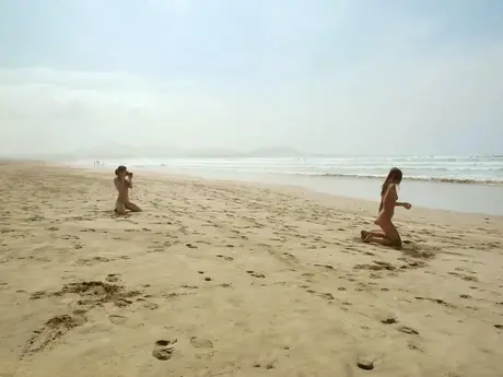 Nakne kvinner på en strand som dekker seg med sand og gjørme