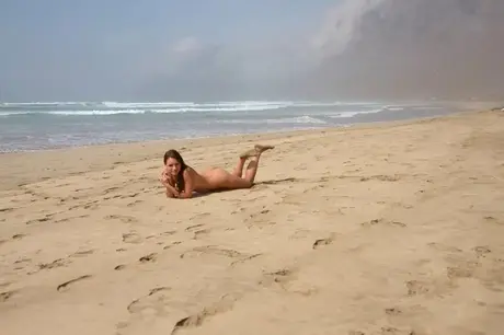 Nakne kvinner på en strand som dekker seg med sand og gjørme