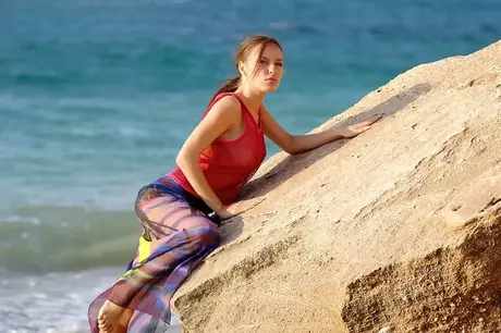 Aurita, una bella ragazza, si spoglia sul suo pareo su una spiaggia di ciottoli