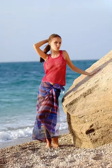 Aurita, una bella ragazza, si spoglia sul suo pareo su una spiaggia di ciottoli