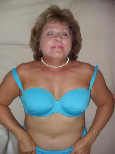 Busty Bliss, vanhempi nainen, nuolee huuliaan ja paljastaa rintansa turkissa